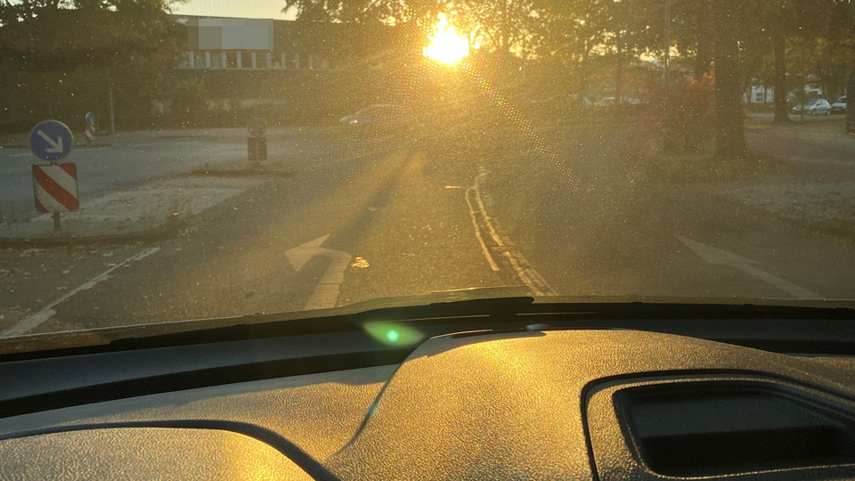 Blick aus dem Cockpit eines Autos auf tiefstehende Sonne