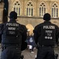 Zwei Polizisten stehen mit dem Rücken zur Kamera vor dem Rathaus von Münster