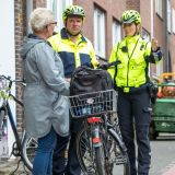 Zwei Polizisten im Gespräch mit einer Seniorin, die neben ihrem Fahrrad steht