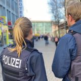 Eine Polizistin und ein Polizist stehen mit dem Rücken zur Kamera und blicken Richtung Hauptbahnhof Münster