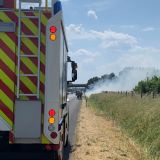 Ein Feuerwehrauto steht einige Meter vor dem stark rauchenden Böschungsbrand