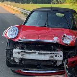Roter Mini Cooper mit stark beschädigter Kühlerhaube am Seitenstreifen der Autobahn