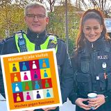 Zwei Polizisten und eine Polizistin vor dem Kaffeestand, davor das Logo der Münsteraner Wochen gegen Rassismus