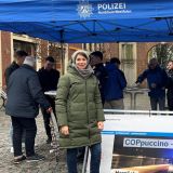 Der "COPpuccino"-Stand in der Julius-Voos-Gasse/Ecke Salzstraße - ein blauer Pavillon mit Polizei-Logo, darunter eine Gruppe von Polizisten und Bürgern im Gespräch