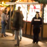 Polizeiwagen links im Vordergrund, im Hintergrund Weihnachtsmarktbuden und Personen