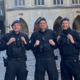 Fünf Polizeibeamte der Hundertschaft vor dem Rathaus in Münster lächeln in die Kamera