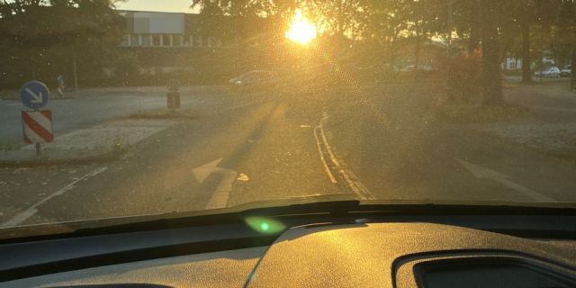 Blick aus dem Cockpit eines Autos auf tiefstehende Sonne