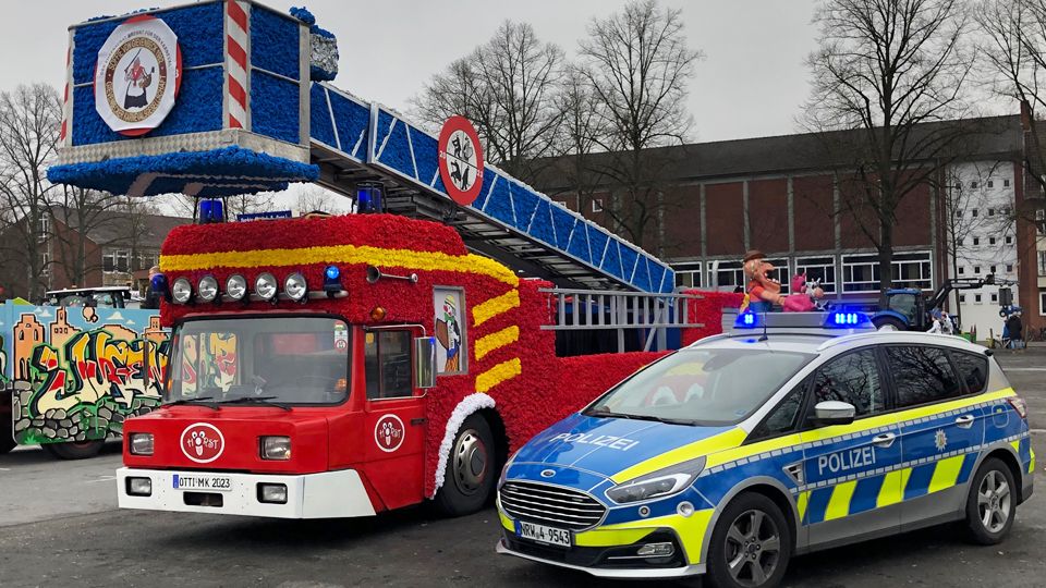 Ein Polizeiwagen und ein Karnevalswagen in Form eines Feuerwehrautos
